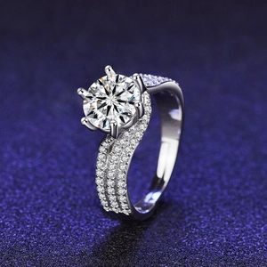 Close-up of a silver six-prong moissanite ring with a twisted pave band on starry background