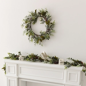 Christmas wreath and garland with pine cones, eucalyptus leaves and white berries on a mantle