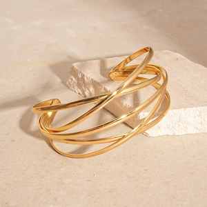 Detailed shot of a layered gold geometric cuff bracelet on a minimalist stone surface
