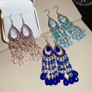 Bohemian crystal teardrop tassel earrings in pink and blue displayed on beige background