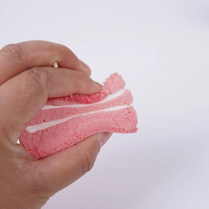 Pink triangle mousse cake squishy toy being squeezed to show slow rebound texture