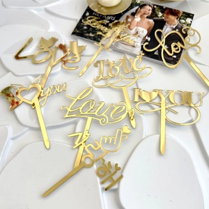 Detailed view of golden acrylic 'Love' and 'I love you' cake toppers for wedding decor