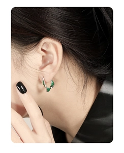 Close-up of a S925 sterling silver U-shaped hoop earring with green drip glaze detail