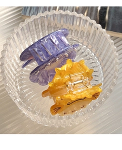 Detailed shot of purple textured and yellow cartoon acetate hair claws in a glass bowl