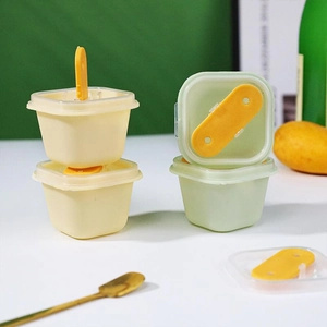 Detail showing square popsicle molds with clear lids and yellow handles on a green background