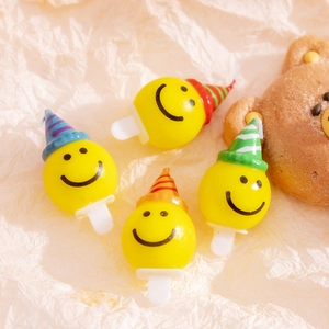 Detailed view of yellow smiley face birthday candles wearing colorful party hats for cakes
