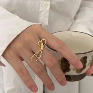 Detail of a golden bow ring with sparkling crystals worn by a model in elegant setting