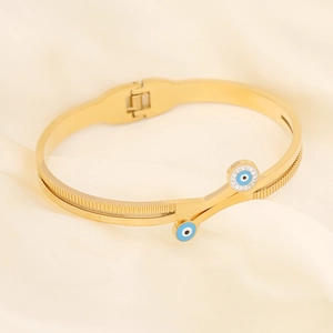 Detail of gold evil eye bracelet with blue enamel and rhinestones on silk background