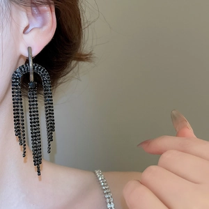 Détail de longues boucles d'oreilles à pompons en strass noirs portées par un mannequin