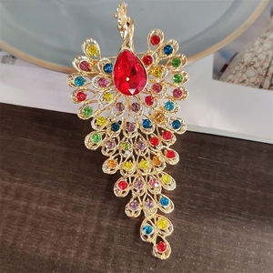 Macro view of colorful crystal peacock brooch with a red teardrop-shaped gemstone