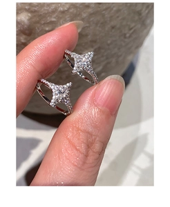 Detailed close-up of silver star earrings with pavé zircon held by hand for scale