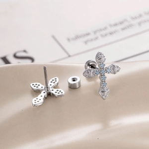 Sweet cross stud earrings with micro-inlaid blue and clear zircons on beige background