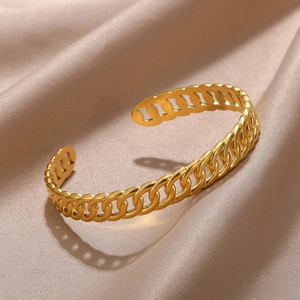 Detail of golden Cuban link texture on adjustable open cuff bracelet over silk