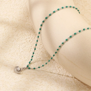Macro detail of S925 silver necklace featuring green beads and a pearl shell pendant