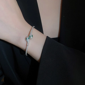 Exaggerated silver snake bangle with green gemstone eyes and sparkling zircon inlay