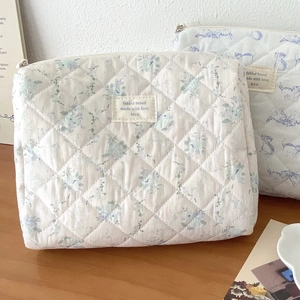 Detail of blue floral quilted cotton makeup bag showing diamond texture and label
