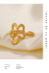Detailed macro shot of a vintage gold hollow flower ring on soft cream silk background