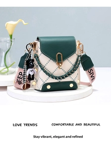 Detail of color-block leather bucket bag with geometric stitching and wide woven strap