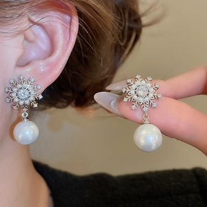 Detail of snowflake zircon earrings with pearls showing exquisite craftsmanship on skin