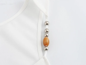 Close-up of white camisole strap featuring elegant silver and amber beaded detail