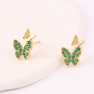 Close-up of golden butterfly earrings with micro-set green emerald cubic zirconia detail