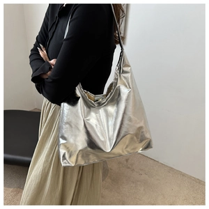 Close-up of metallic silver tote bag with glossy finish on a shoulder-worn model