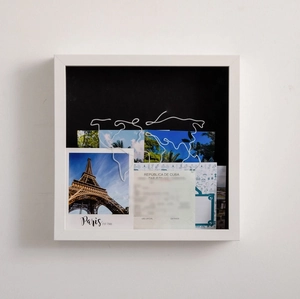 Macro shot of white shadow box frame with travel cards and wire world map detail