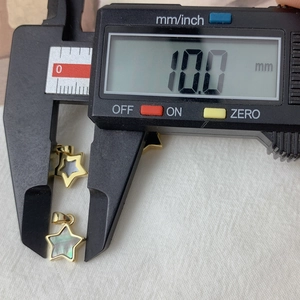 Vue macro de deux pendentifs étoile en or avec nacre, montrant une mesure de 10,0 mm