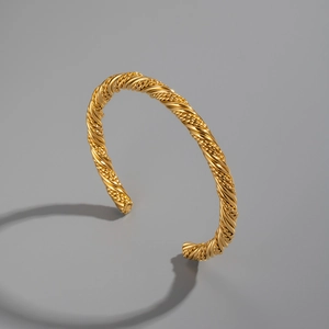 Detailed macro view of 18K gold plated twisted rope texture on a minimalist cuff bracelet