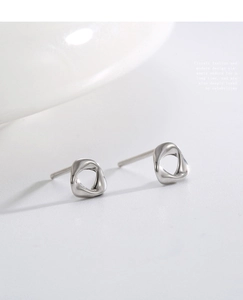 Close-up of geometric hollow twisted silver stud earrings with minimalist metal texture