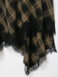 Détail du tissu à carreaux marron et de la dentelle délicate noire sur la jupe en gros plan