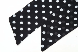 Detail of polka dot chiffon scarf showing the sharp corner cut and translucent fabric texture