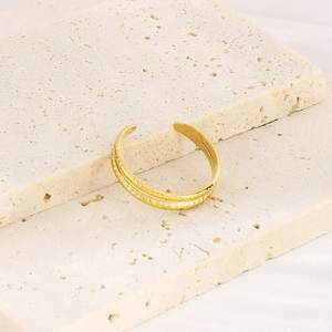 Detail of 18k gold plated double-layer open ring on cream travertine stone