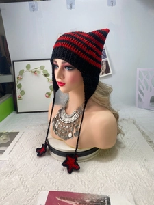 Close-up of knit cat ear hat with red and black stripes and star pendant details