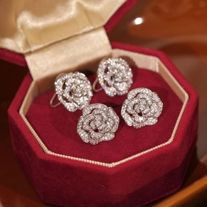 Vue macro détaillée de boucles d'oreilles camélia serties de zircons en boîte rouge