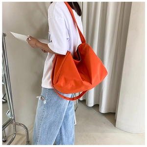 Detail view of large orange oxford fabric gym bag worn by model in minimalist setting