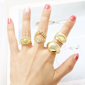 Detail of four gold-plated daisy rings set with sparkling zircons on a model's hand