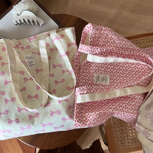 Détail de sacs fourre-tout en toile avec motifs de nœuds roses et étiquettes tissées