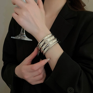 Macro detail of glossy silver irregular wave cuff bracelet in polished metal finish