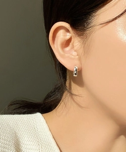 Close-up of a sterling silver hoop earring with starburst engraving on a female model