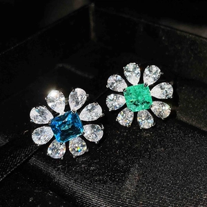 Detail view of flower-shaped stud earrings with blue and green gems in a black jewelry box