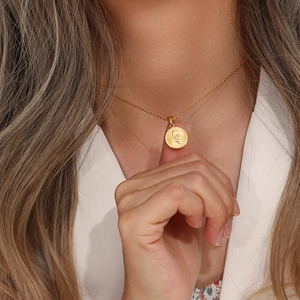 Close-up of gold snake pendant necklace worn by a model in a white blazer