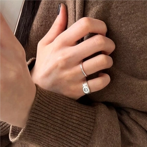 Detail of S925 sterling silver smiley face ring and minimalist band on a finger