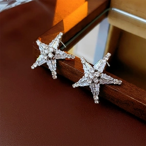 Dettaglio macro di orecchini a stella in argento con zirconi su superficie in pelle