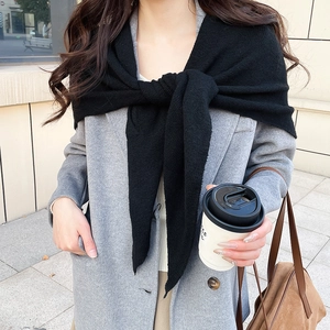 Détail d'un châle en tricot noir à texture fine drapé sur un manteau en laine grise