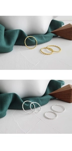 Macro shot of gold and silver twisted stackable rings on a white and green studio background