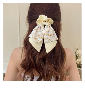 Floral print bow hair scrunchie with yellow fabric ribbon on brown wavy hair