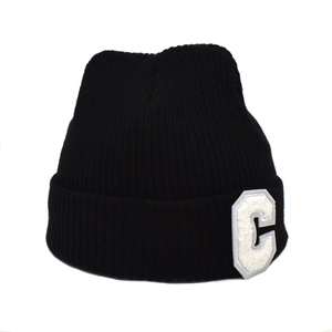 Détail du bonnet en maille côtelée noire avec écusson blanc en lettre C sur le revers