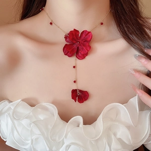 Detailed macro view of the dark red fabric flower pendant on a golden Y-shaped necklace