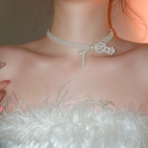 Détail d'un collier de perles avec nœud sur un mannequin sous une lumière douce